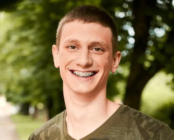 Teen smiling with braces outdoors, representing the experience of wearing braces and addressing common concerns about discomfort during orthodontic treatment.