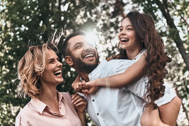 Happy family enjoying outdoor fun, smiling and laughing together, emphasizing joy and connection after orthodontic appointments.